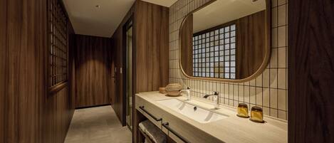 A modern bathroom with wooden paneling, a large mirror, and a dual sink vanity.