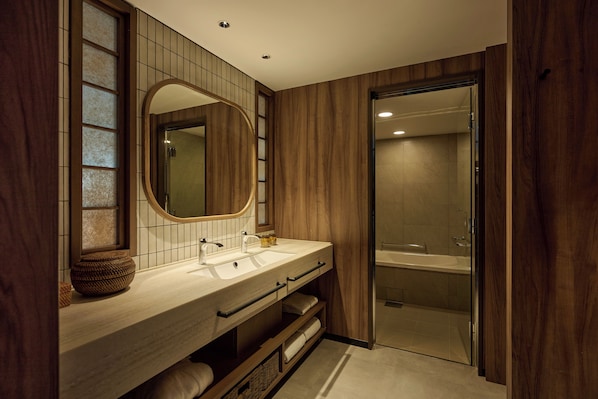 A modern bathroom with a wooden vanity, a large mirror, and a glass shower enclosure. - The Royal Park Hotel Iconic Naha (Naha)