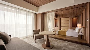 Een moderne hotelkamer met een houten plafond, een ronde tafel, een bank, een bed en een nachtkastje met een lamp.