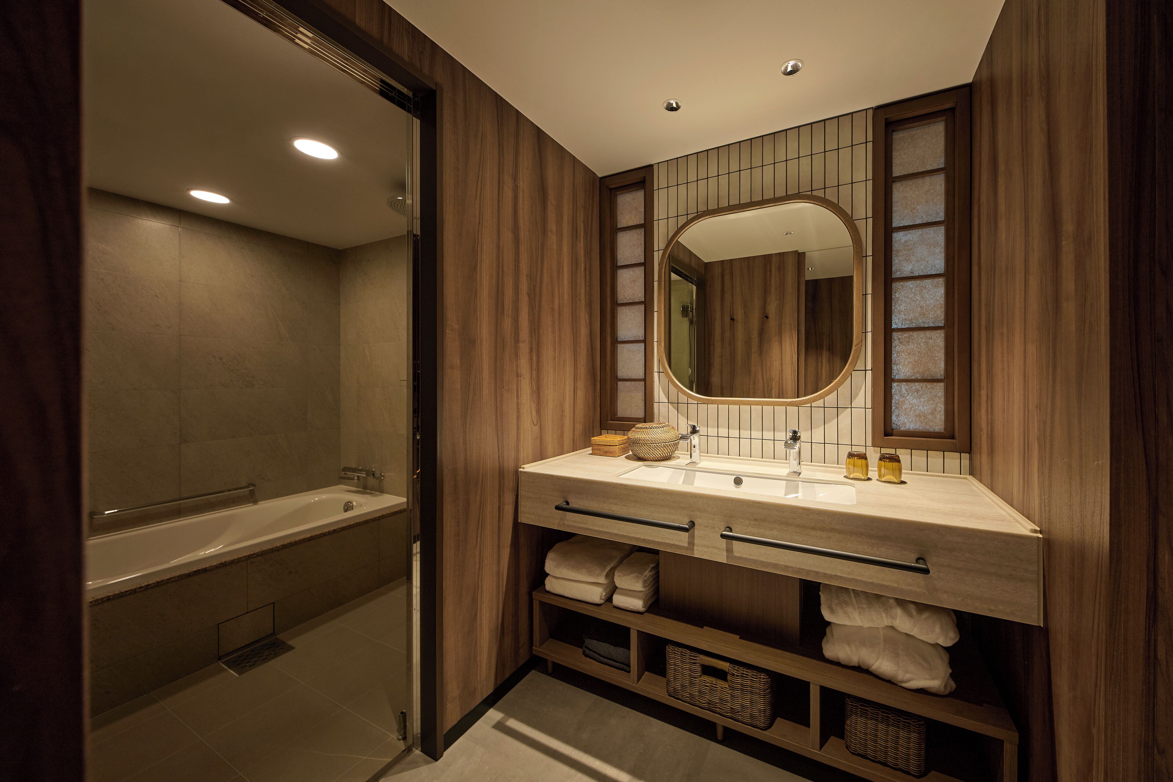 A modern bathroom with a bathtub, a vanity with a mirror, and storage shelves.