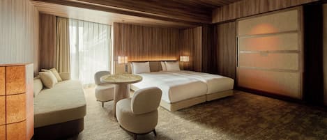 Une chambre d’hôtel avec un grand lit, un coin salon avec une table et une armoire.