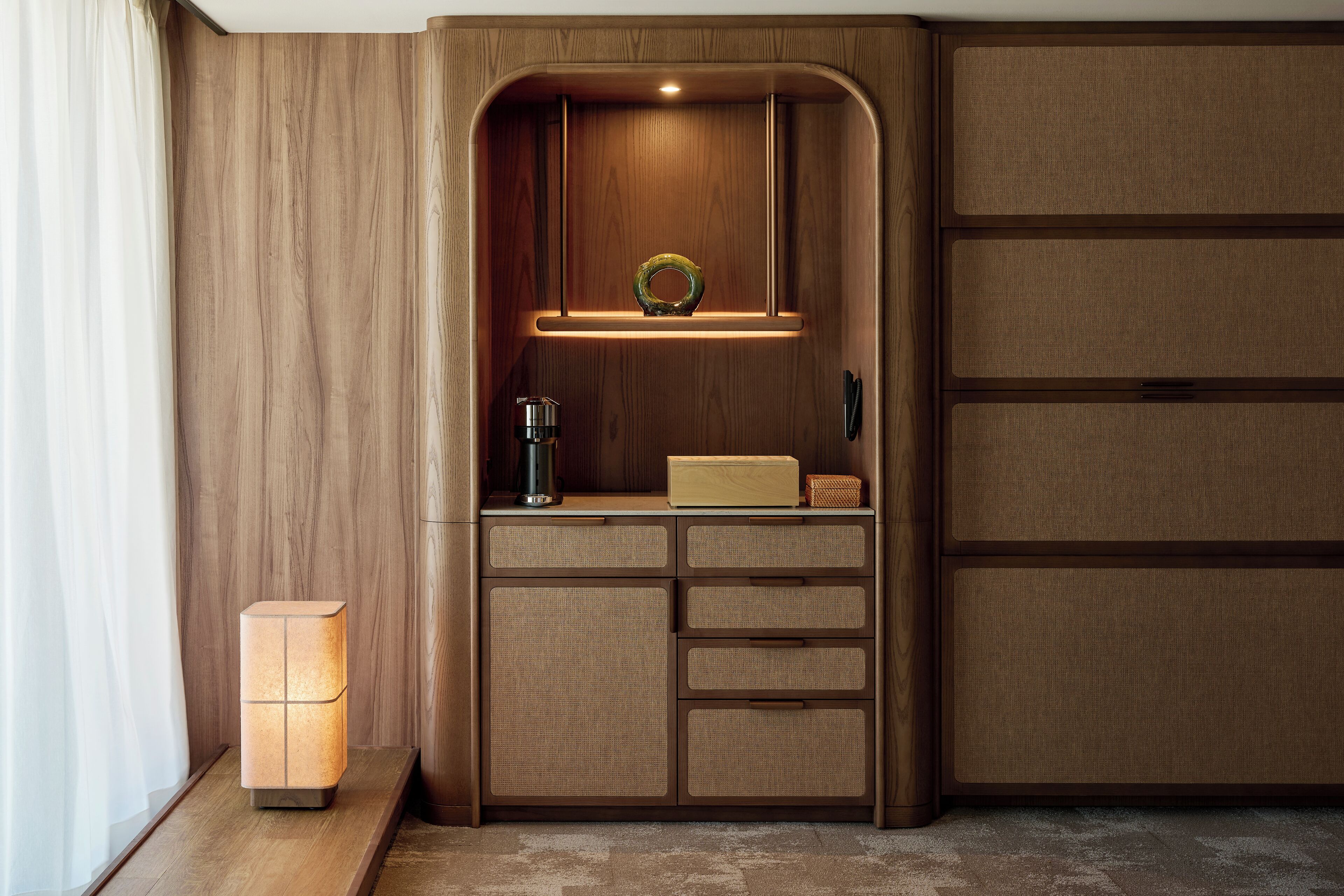 Una kitchenette compacta y moderna con armarios empotrados, una encimera y un colgante.