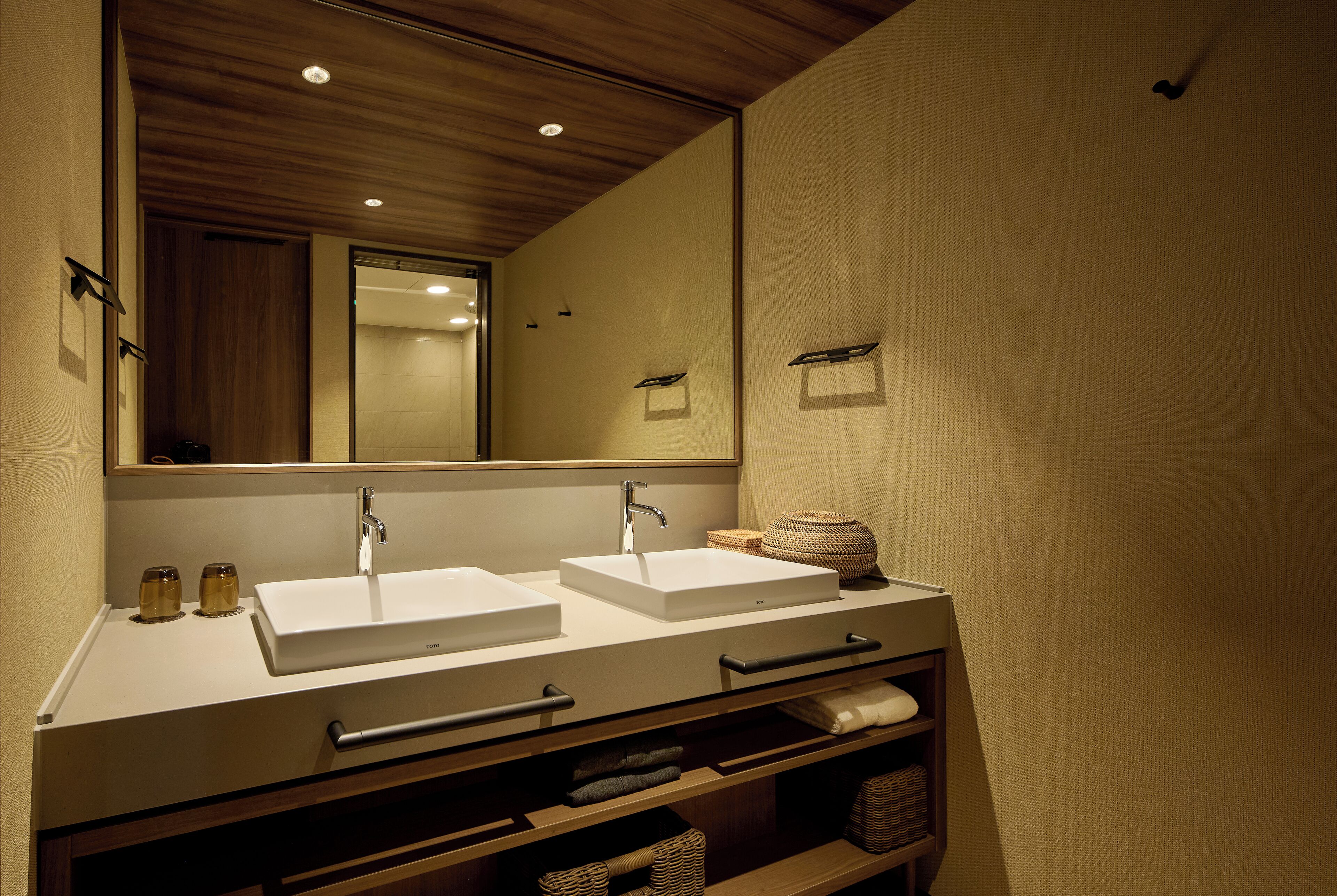 A modern bathroom with two sinks, a large mirror, and built-in storage.