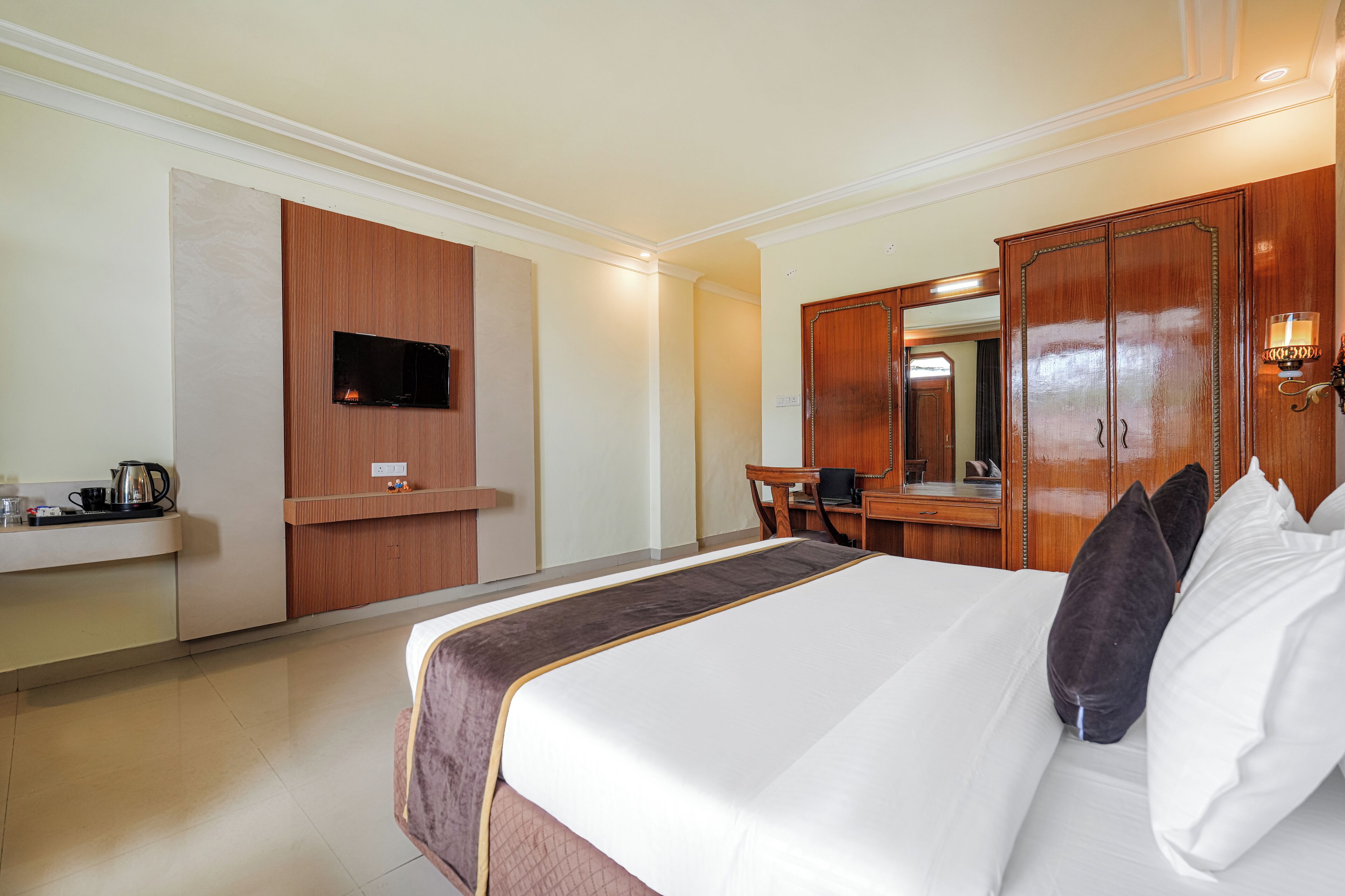 Una habitación de hotel con una cama grande, un escritorio, un televisor montado en la pared y un armario.