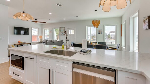 Une cuisine moderne avec des meubles blancs, un grand îlot central et des luminaires suspendus.