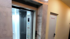An elevator with a control panel and a door with a handle.