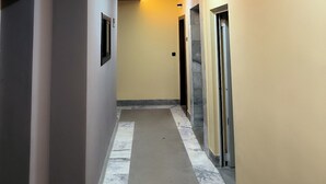 A hallway with a curved ceiling design, recessed lighting, and a marble floor.