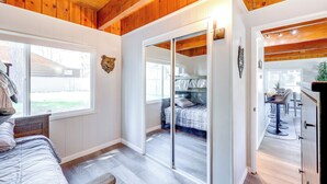 Ein Schlafzimmer mit einer großen Schiebeglasdoor zum Balkon, Holzboden und Blick auf den Garten.