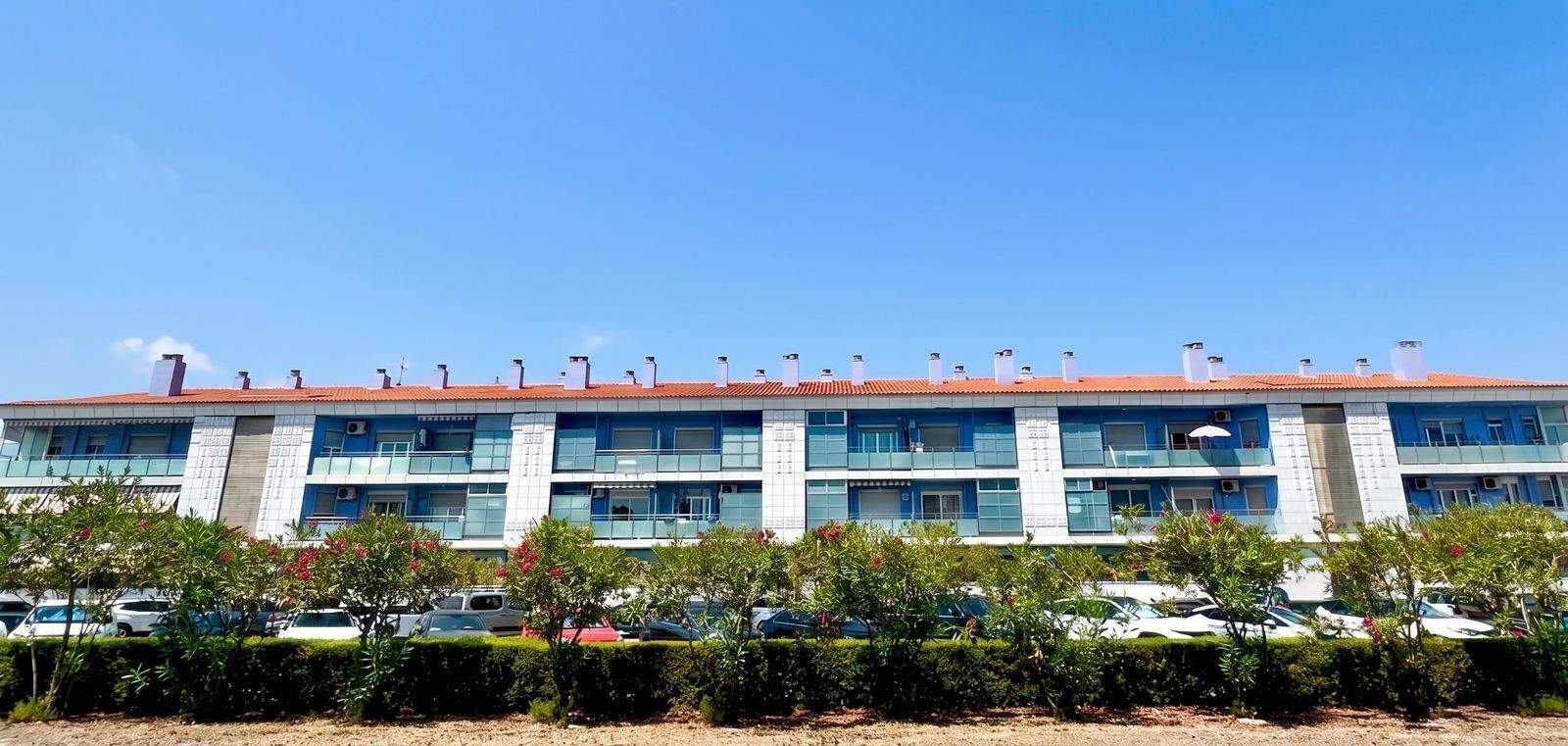 Un immeuble à plusieurs étages, doté d’un toit recouvert de tuiles rouges, de nombreux balcons et de climatiseurs.