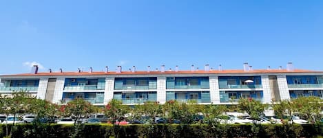 A multi-story building with a red-tiled roof, multiple balconies, and air conditioning units.