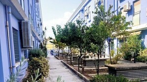 A narrow street with blue buildings, trees, and a clear sky. - FIRST LINE BEACH PARTMENT (València)