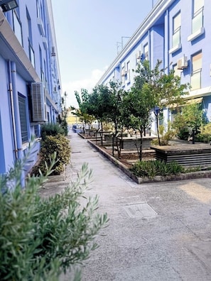A narrow street with blue buildings, trees, and a clear sky. - FIRST LINE BEACH PARTMENT (València)