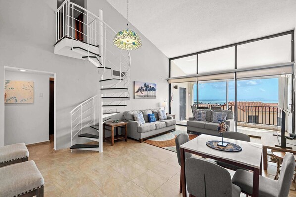 A spacious living area with a staircase, a dining table, and a sofa.