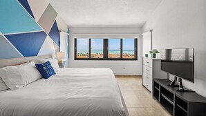Une chambre d’hôtel moderne avec un grand lit, une télévision et une vue sur la plage.