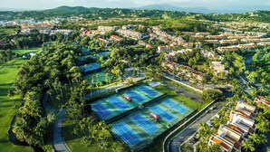 Un quartier résidentiel doté de plusieurs courts de tennis, entouré d’une végétation luxuriante et de palmiers.