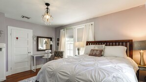 Une chambre à coucher avec un grand lit, une table de chevet, une chaise, un miroir et un lustre.