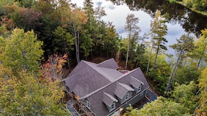 A two-story house with a steep roof, surrounded by dense forest and a lake. - Lakefront luxury,GameRoom,FirePit,Canoe,10Min2JFBB (Blakeslee)