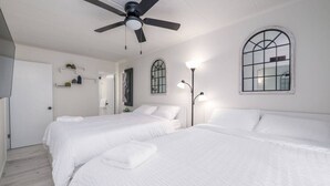 A hotel room with two beds, a ceiling fan, a large arched window, and a floor lamp. - Downtown OC Condo with Bay View, Pool, Parking, Walk to Beach & Boardwalk (Ocean City)