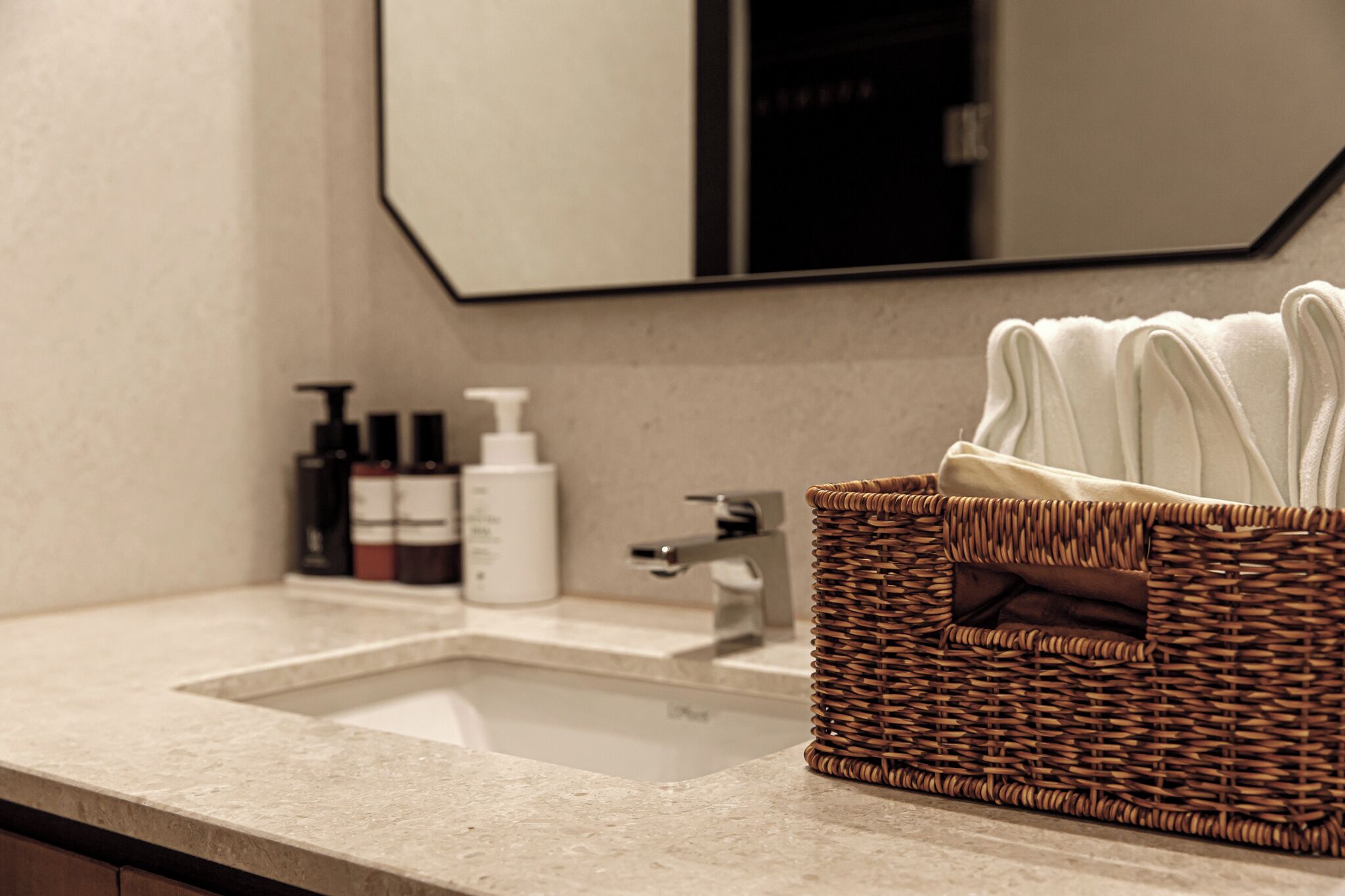 Un bagno con lavandino, specchio e cesto in vimini con asciugamani.