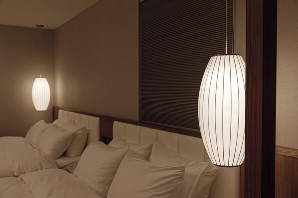 A hotel room with a bed, two wall-mounted lamps, and a window with blinds.