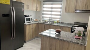 A modern kitchen with wooden cabinets, a stainless steel refrigerator, a microwave, and a granite countertop. - Comfort & Privacy:Family, Couple - rent Villa in Punta Cana with A/C, WIFI, POOL (Punta Cana)