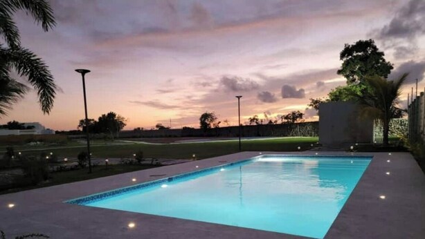 A rectangular swimming pool with a dark-colored deck, surrounded by a low wall and palm trees. - Comfort & Privacy:Family, Couple - rent Villa in Punta Cana with A/C, WIFI, POOL (Punta Cana)