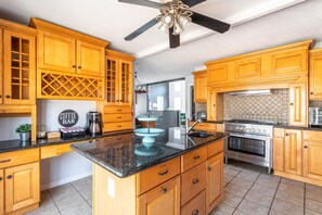 A kitchen with wooden cabinets, a granite countertop, a built-in oven, and a ceiling fan.