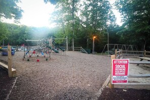 An outdoor playground with a sign about social distancing.