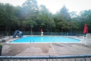 A rectangular swimming pool with a ladder and a lifeguard chair.