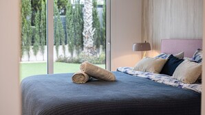 Una camera da letto con un'ampia finestra, un letto con copriletto blu e una lampada su un comodino.