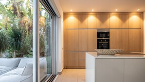 Una cucina moderna con mobili in legno, forno integrato e un'ampia finestra con vista su un giardino.