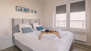 A bedroom with a bed, a bedside table, a window, and a radiator.
