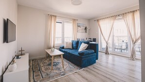A modern living room with a blue sofa, a small table, and a TV.