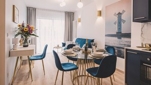 A modern dining area with a round table, blue chairs, and a view of a windmill through a window.