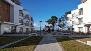 A modern residential building with a central pathway, balconies, and a clear sky.