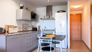 A modern kitchen with white cabinets, a built-in microwave, a stove, and a dining area with a table and chairs.