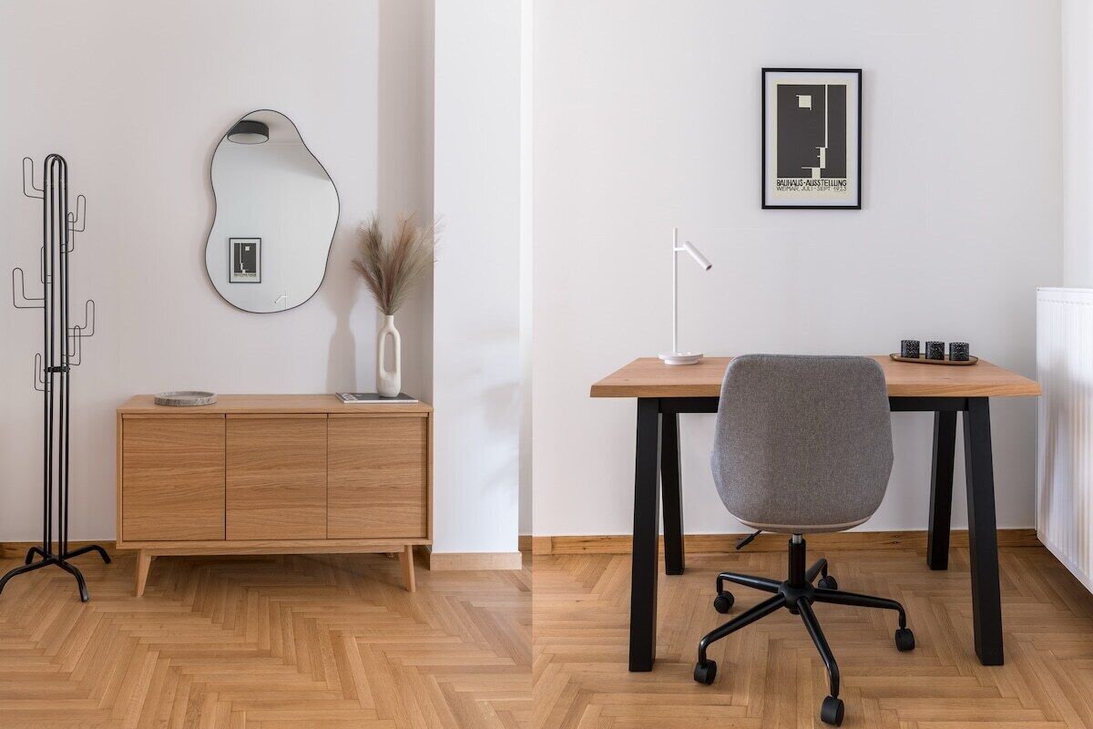 A modern office space with a wooden desk, a grey office chair, a standing lamp, a mirror, and a radiator.