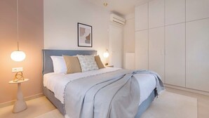 A bedroom with a bed, bedside tables, a wardrobe, and an air conditioning unit.