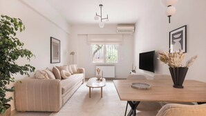 A modern living room with a beige sofa, a coffee table, a dining table, and a potted plant.