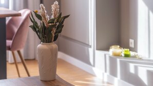 A wooden table with a vase of dried flowers and a magazine. - Monastiraki Living: Deluxe 2BR Apartment (Athens)