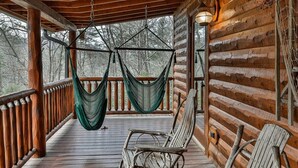 A wooden deck with a hammock, a chair, and a lantern.