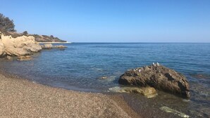 A rocky shoreline with clear water and a distant view of the sea.