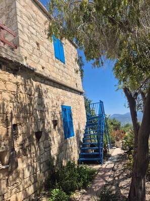 A stone building with blue shutters and a blue staircase leading to a door.