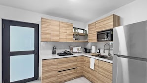 Una cocina moderna con armarios de madera, un refrigerador de acero inoxidable, un microondas y un fregadero.