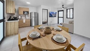 Una cocina moderna con armarios de madera, electrodomésticos de acero inoxidable y un comedor con una mesa redonda para cuatro personas.