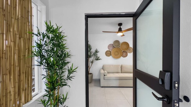 Ein modernes Wohnzimmer mit einer Couch, einem Deckenventilator und Wanddekoration.
