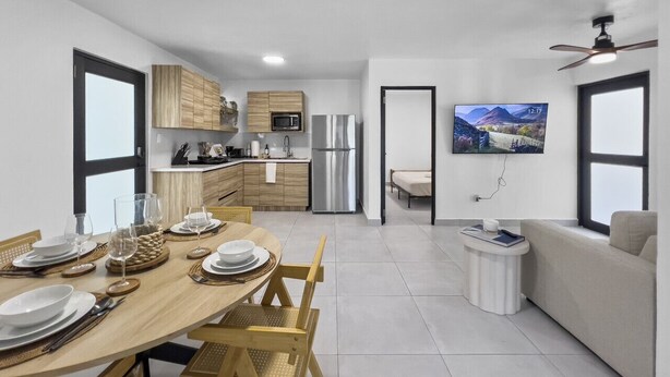 Una cucina moderna con mobili in legno, un frigorifero in acciaio inossidabile e un'area pranzo con un tavolo di legno apparecchiato per quattro persone.