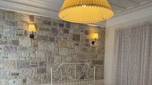 Een slaapkamer met twee bedden, een stenen muur, een wit plafond en een gele hanglamp.