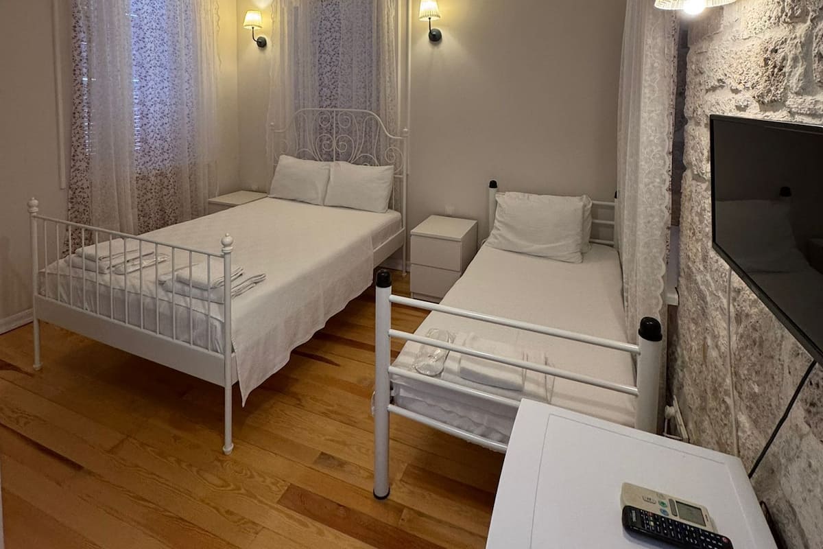 Ein Schlafzimmer mit zwei Betten, einem Fernseher und einer Fernbedienung auf einem weißen Schrank.