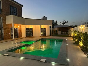 A modern house with a swimming pool, a covered patio, and a well-lit garden area. - Splendid villa in Warang (Warang)